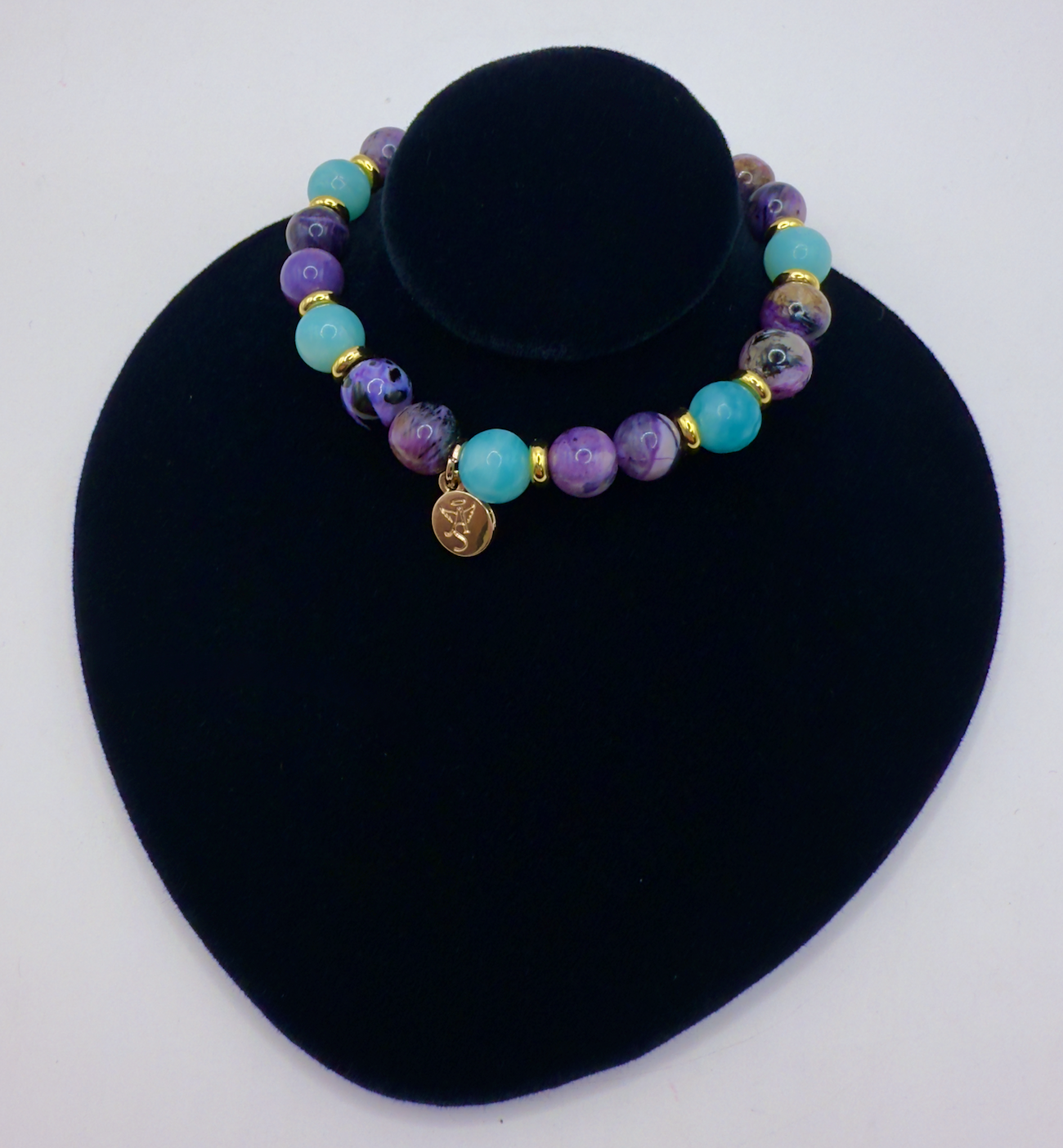 Transformation Bracelet with Amazonite, Charoite, and Sugilite beads on black display stand