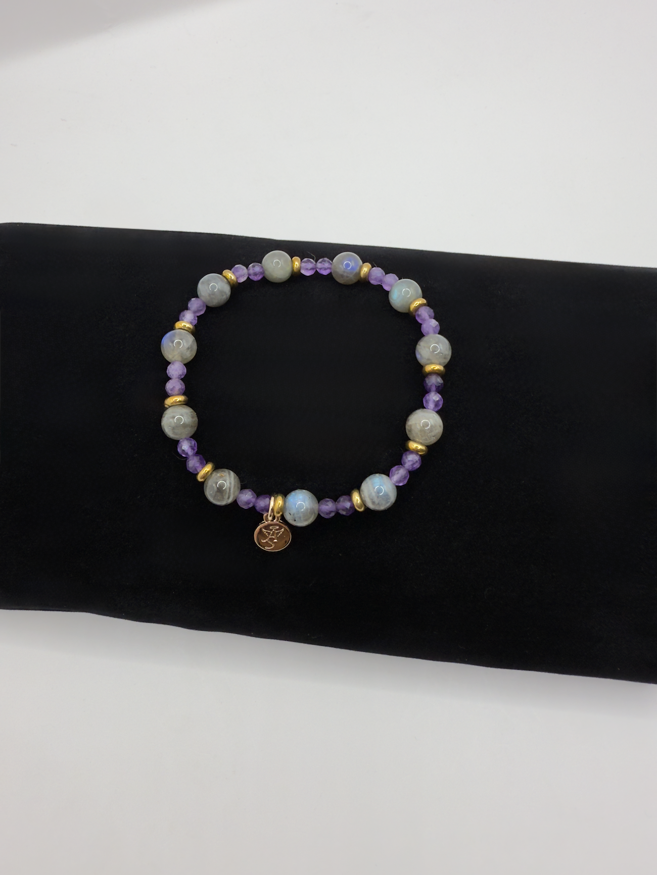 Celestial Harmony Bracelet with labradorite and amethyst beads accented by gold spacers and angel charm on black background