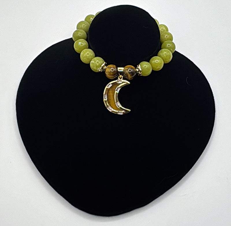 Strength Resilience Bracelet with green serpentine beads, tiger eye stones, and a tiger eye waning moon charm on a black display stand