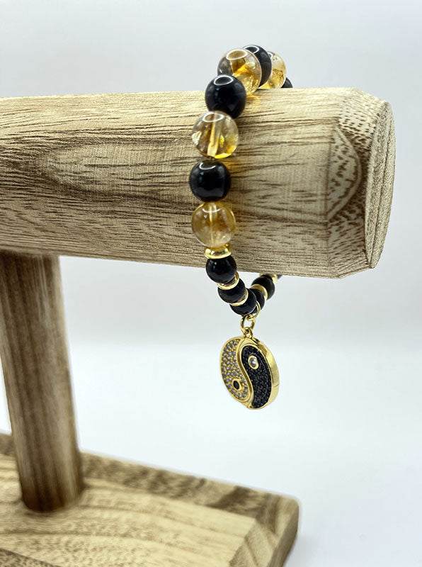 Yin Yang Bracelet with golden obsidian and citrine beads and a gold yin yang charm on wooden display stand