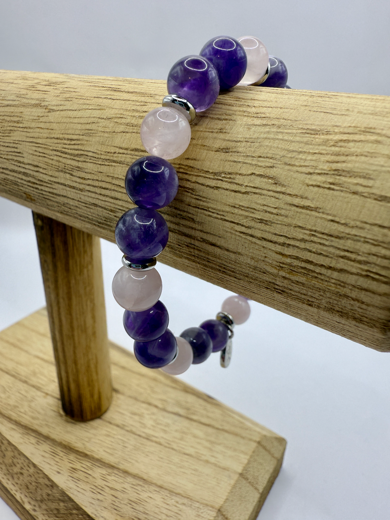 Harmony Bracelet with natural amethyst and rose quartz beads on a wooden display stand