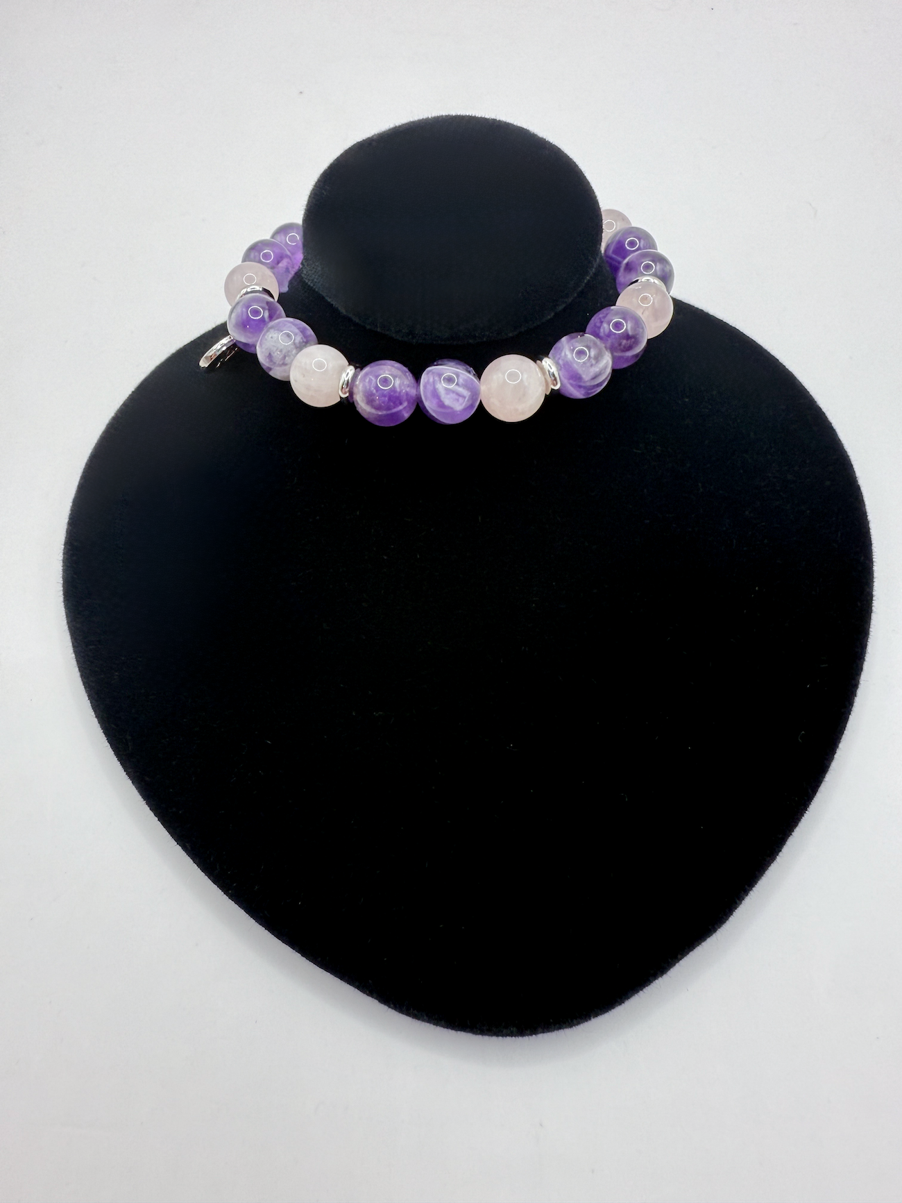 Harmony Bracelet with natural amethyst and rose quartz beads on stretch cord with Angel Stones charm displayed on black stand