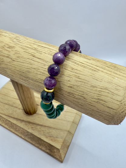 Limited edition Wicked Bracelets featuring Elphaba-inspired emerald, ruby, and zoisite beads on wooden display stand