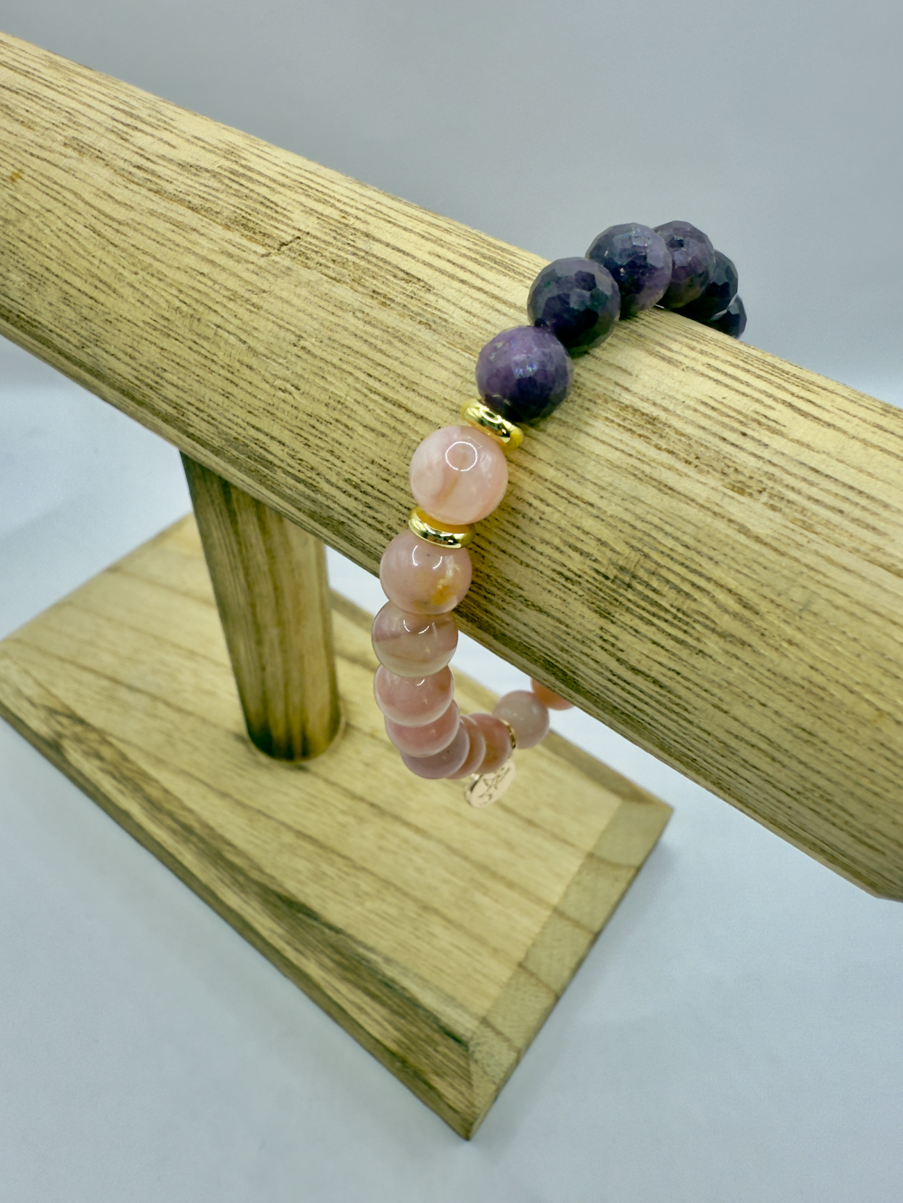 Limited edition Wicked Bracelets Glinda with pink opal and ruby beads on wooden display stand