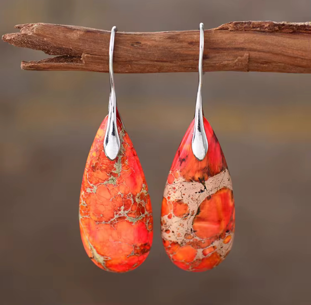 Ember Path Jasper Drop Earrings with burnt orange and ember red teardrop stones and silver-tone hangers hanging on a wooden branch