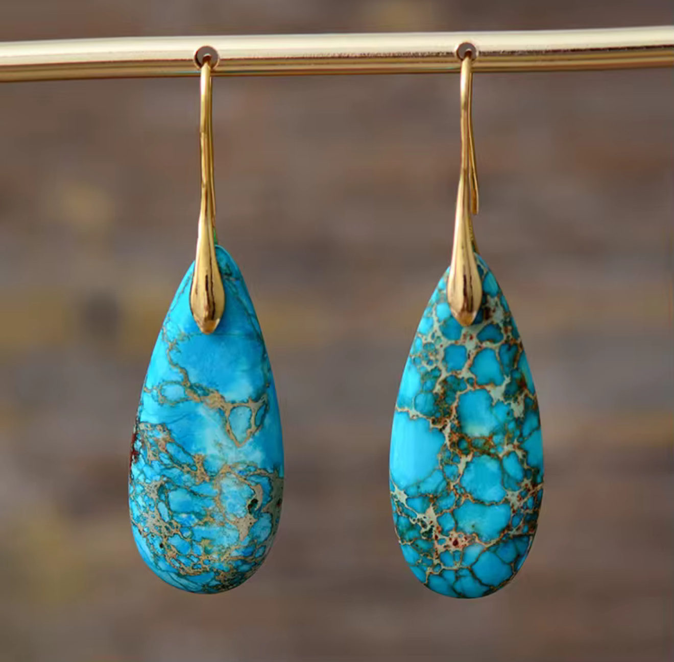 Close-up of Turquoise Path Jasper Drop Earrings with turquoise blue teardrop stones and gold-tone hangers displaying natural veining patterns