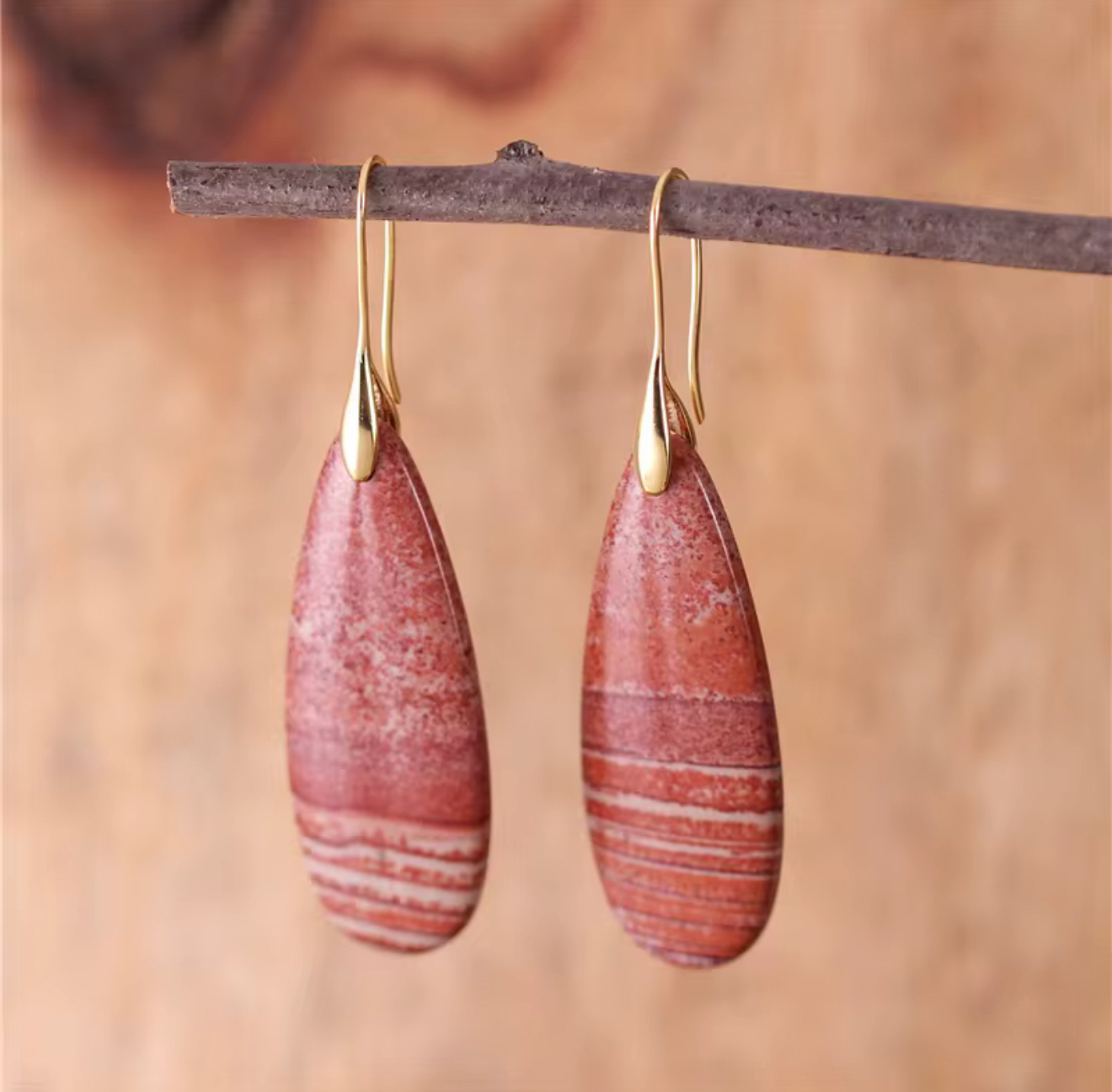 Desert Ember Jasper Drop Earrings with rust red jasper stones and gold-tone hooks hanging on a branch