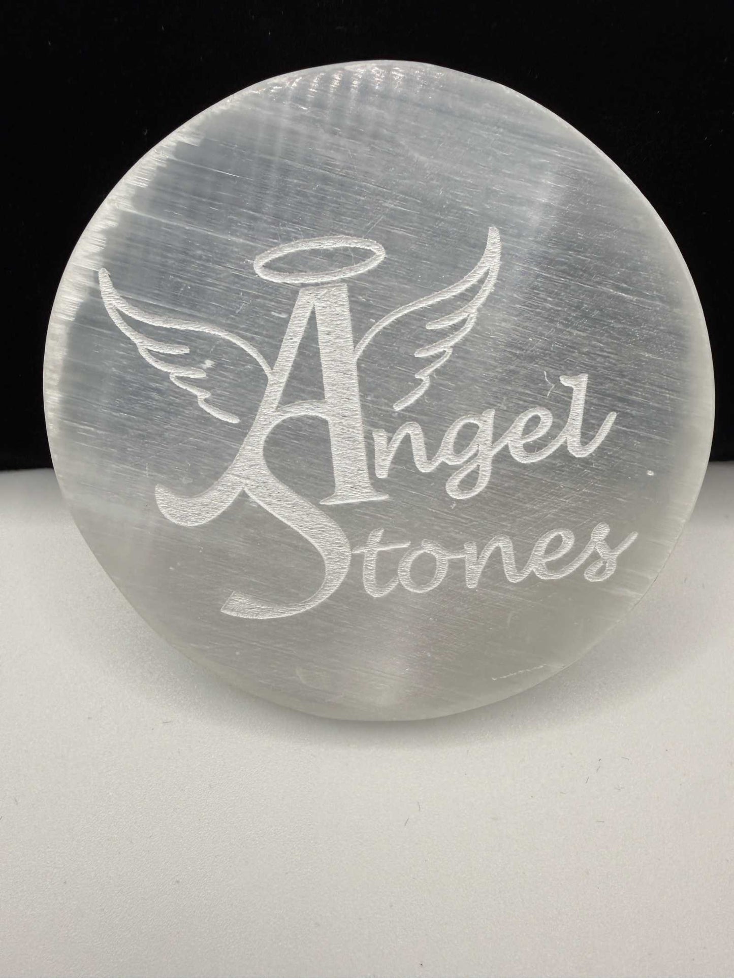 Selenite charging plate with engraved Angel Stones logo and luminous glow